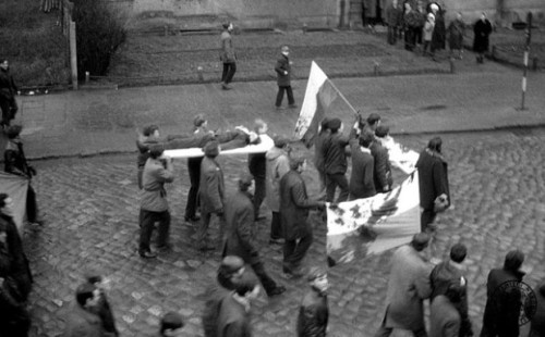 PHOTO: EAST NEWS/IPN  Demonstracje na terenie miast Wybrzeza Gdanskiego, 14-22.12.1970 r.  N/Z: Protestujacy maszeruja ulicami Gdyni, niosac na drzwiach cialo Zbigniewa Godlewskiego (znanego tez jako Janek Wisniewski) - robotnika zastrzelonego 17 grudnia 1970 r., prawdopodobnie przez zolnierzy Ludowego Wojska Polskiego. W chwili smierci mial 18 lat. Obok ciala - zakrwawione flagi narodowe.    Demonstrations in the area of Gdansk Bay's cities, 14-22.12.1970.  Photo: Zbigniew Godlewski's body (also known as "Janek Wisniewski") is carried on doors through the cordons of police and tanks. The 18-year worker was killed in the Polish city of Gdynia by the military or police on December 17, 1970. Nearby the body - the Polish national flags covered in blood.