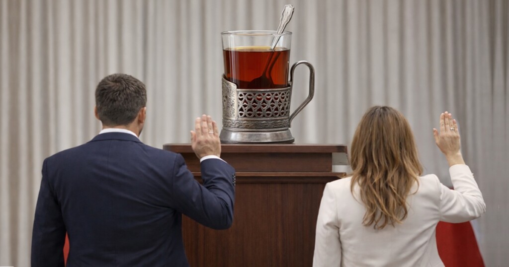 Osoby składające ślubowanie z uniesioną ręką przed szklanką herbaty w metalowym koszyczku